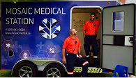 Side view of a Mosaic Medical ambulance with two male employees standing at the door with the door open.