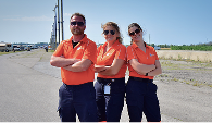 A team of three Mosaic Medical medics posing with arms crossed. They are wearing the orange polo.