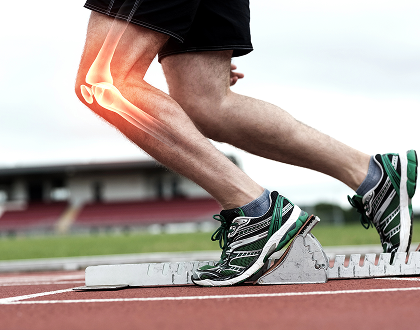 A runner's legs are shown on a track, highlighted with a glowing effect at the knee, suggesting joint strain. Green sneakers and a blurred stadium in the background.
